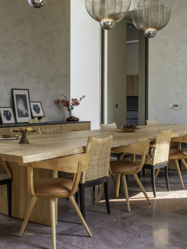 Long wooden live edge dining table with natural curves and visible wood grain, seats six.